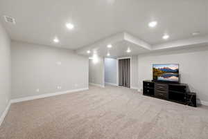 Finished below grade area featuring light colored carpet and recessed lighting
