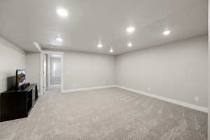 Finished below grade area with light colored carpet and recessed lighting