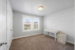 Unfurnished bedroom with light colored carpet and baseboards