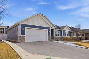 Craftsman inspired home with stone siding, driveway, and a garage