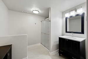 Bathroom featuring vanity, a stall shower, and a textured ceiling