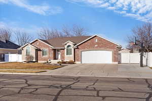 Single story home featuring a gate, concrete driveway, brick, stucco, and a garage