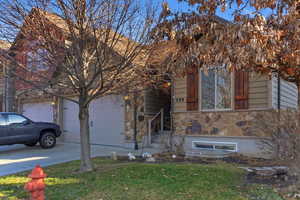 View of front facade with concrete driveway, stone siding, an attached garage, and a front yard