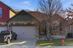 View of front of home with stone siding, board and batten siding, and driveway