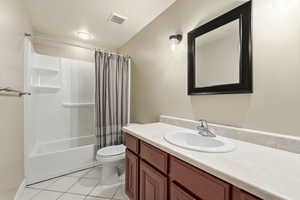 Full bath featuring vanity, shower / tub combo with curtain, and light tile patterned floors