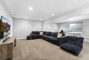 Living area with light carpet and recessed lighting