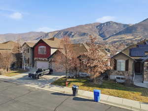 Craftsman-style home featuring board and batten siding, driveway, a mountain view, stone siding, and a front lawn