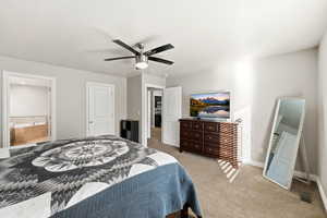 Bedroom with light carpet, ensuite bath, and a ceiling fan