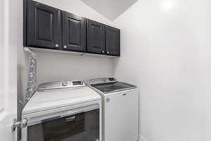 Laundry area with cabinet space, lofted ceiling, and washer and clothes dryer