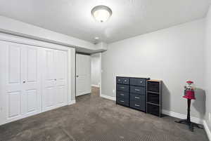 Unfurnished bedroom with a closet, dark carpet, and a textured ceiling