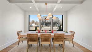 Dining space with wood finished floors, a chandelier, and beamed ceiling