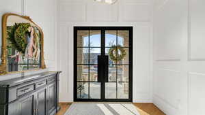 Doorway to outside featuring a decorative wall, french doors, and wood finished floors