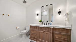 Bathroom featuring vanity, a shower, vaulted ceiling, and light tile patterned flooring