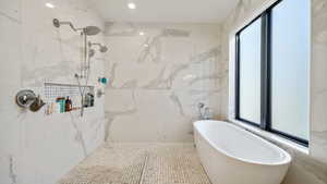 Bathroom with a freestanding tub and a marble finish shower