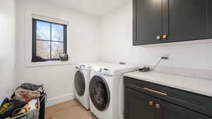 Laundry area featuring cabinet space, light wood-type flooring, and washing machine and clothes dryer