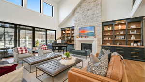 Living area featuring a high ceiling, a stone fireplace, and light wood-type flooring