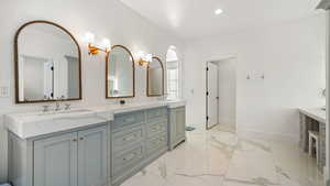 Full bath with double vanity, light marble finish flooring, and recessed lighting