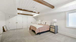 Bedroom with two closets, a ceiling fan, carpet, and a wooden ceiling with exposed beams