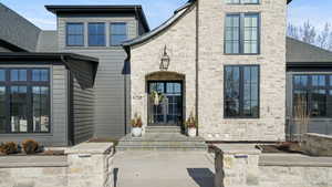 Property entrance featuring stone siding and a shingled roof