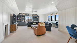 Living room featuring wooden walls, light carpet, recessed lighting, ceiling fan, and a fireplace