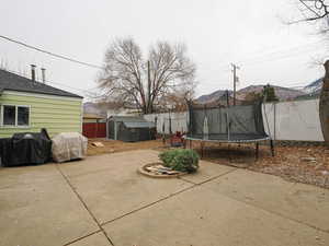 Fenced backyard with grilling area, a trampoline, and a storage shed