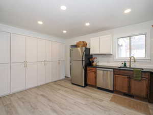 Dual tone kitchen with stainless steel appliances, light wood finished floors, recessed lighting, and two tone cabinets
