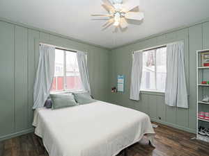 Bedroom featuring dark wood-style flooring, ceiling fan, and multiple windows