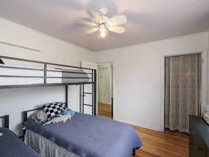 Bedroom with wood finished floors, crown molding, and a ceiling fan