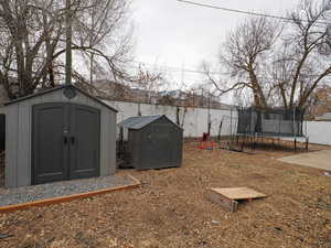 Fenced yard featuring a storage shed and a trampoline