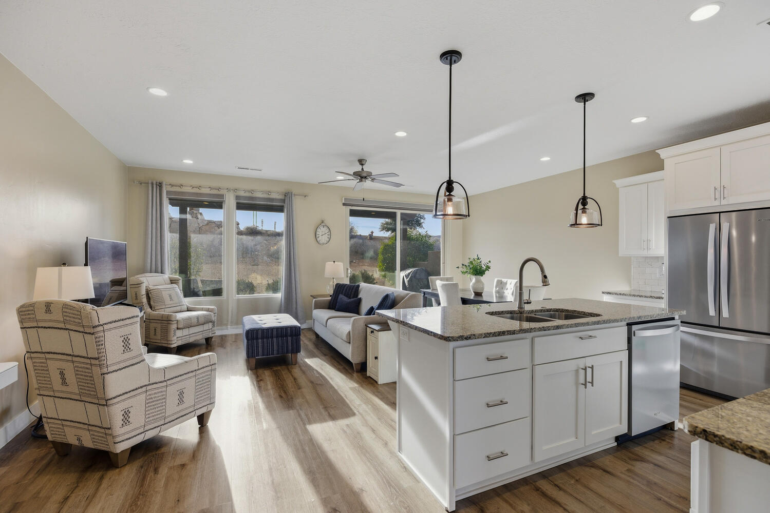 Kitchen featuring stainless steel appliances, white cabinetry, hanging light fixtures, open floor plan, and ceiling fan