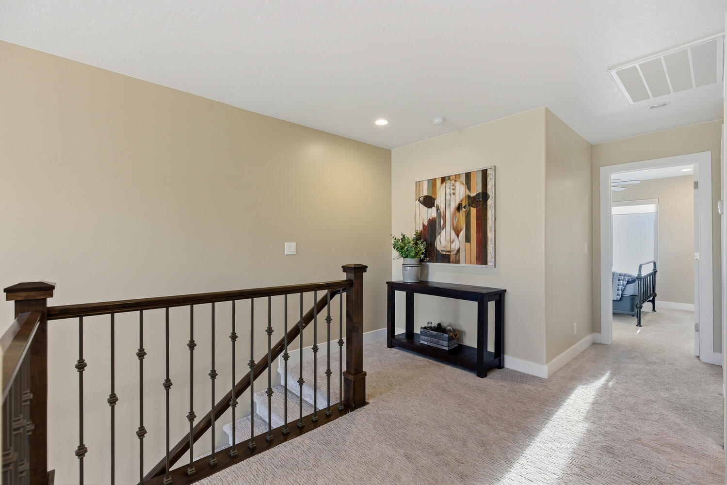 Hallway with light carpet, an upstairs landing, and recessed lighting