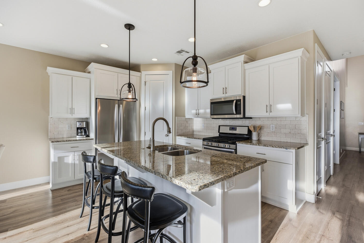 Kitchen featuring dark stone countertops, stainless steel appliances, light wood-style floors, white cabinets, and a breakfast bar