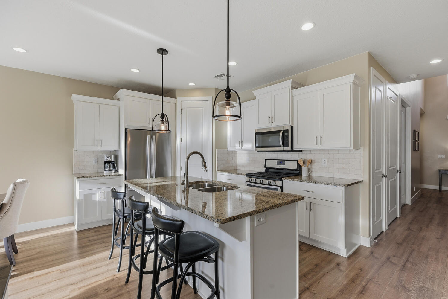 Kitchen featuring stainless steel appliances, a breakfast bar area, dark stone counters, an island with sink, and light wood-style flooring