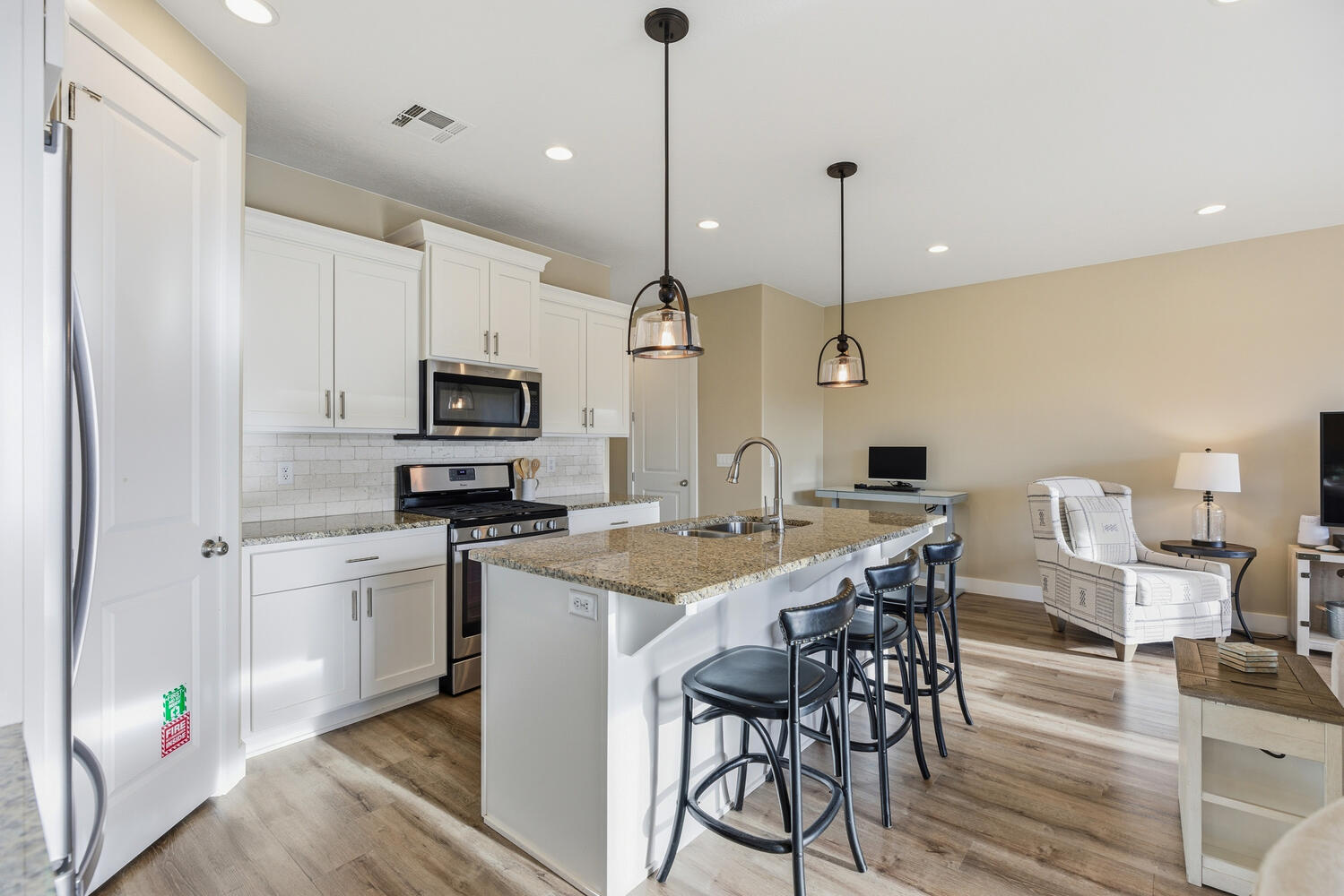 Kitchen featuring stainless steel appliances, a kitchen breakfast bar, light wood-style floors, and white cabinetry