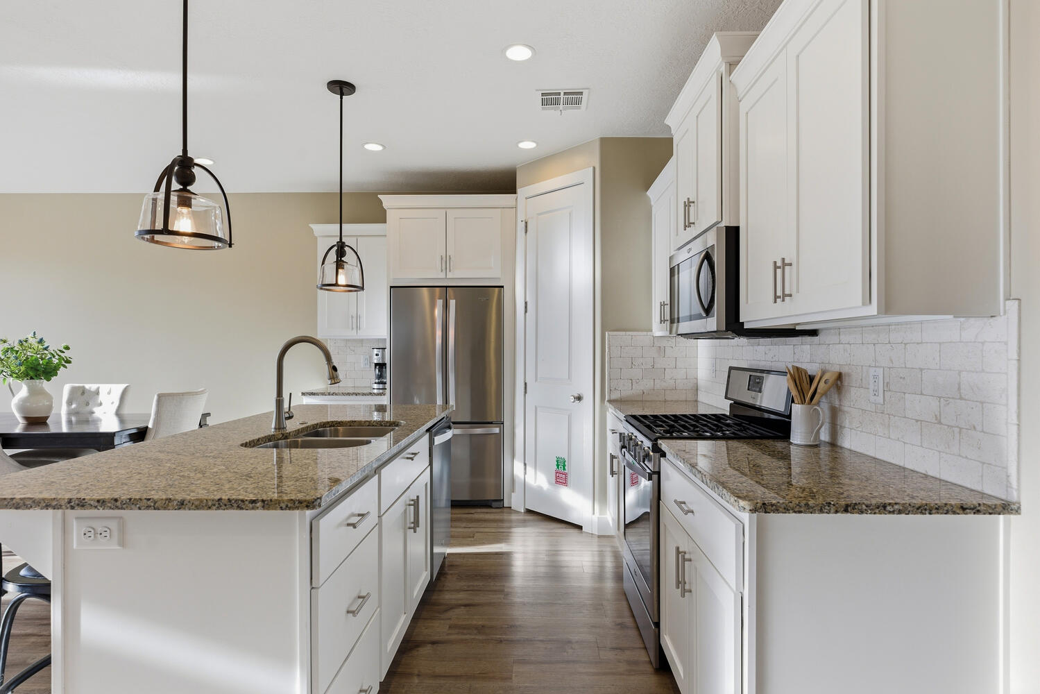 Kitchen with a breakfast bar area, stainless steel appliances, pendant lighting, dark stone counters, and white cabinetry