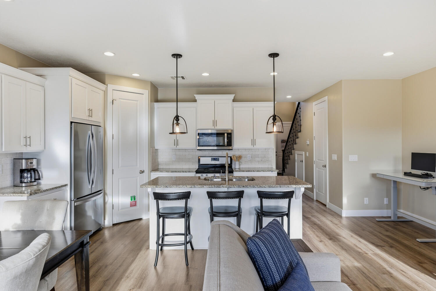 Kitchen featuring a kitchen breakfast bar, stainless steel appliances, white cabinets, and pendant lighting