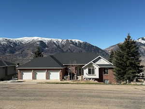 Ranch-style home with a mountain view, a garage, brick siding, and driveway