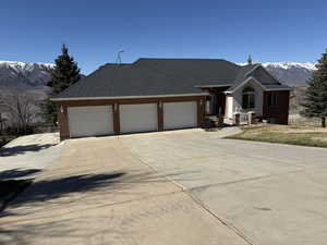 Ranch-style home featuring a mountain view, concrete driveway, brick siding, an attached garage, and a shingled roof