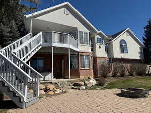 Back of property with an outdoor fire pit, brick siding, and a patio