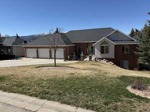 Ranch-style house featuring brick siding, a front lawn, a garage, driveway, and roof with shingles