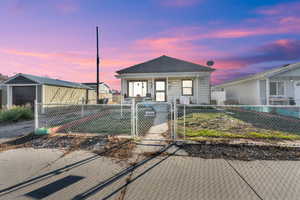 Shotgun-style home with a gate and a fenced front yard