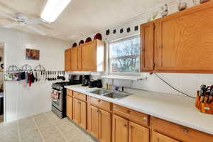 Kitchen featuring stainless steel range with gas cooktop, light countertops, ceiling fan, tile walls, and backsplash