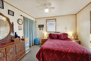 Bedroom with light colored carpet, ceiling fan, and crown molding