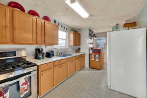 Kitchen featuring stainless steel gas stove, freestanding refrigerator, light countertops, and plenty of natural light