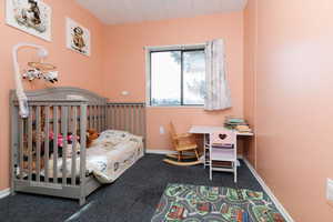 Carpeted bedroom featuring a crib and baseboards