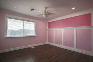 Spare room with ceiling fan, dark wood finished floors, and ornamental molding