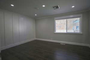 Bedroom with dark wood finished floors, ensuite bathroom, recessed lighting, and ornamental molding