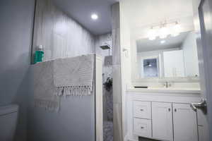 Ensuite Bathroom with vanity, a tile shower, and recessed lighting
