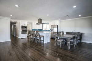 Dining space featuring dark wood-style floors, recessed lighting, a textured ceiling, and crown molding