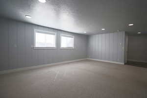 Empty room with carpet floors, a textured ceiling, and recessed lighting